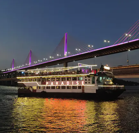 Triple-decker party cruise with string lights at dusk